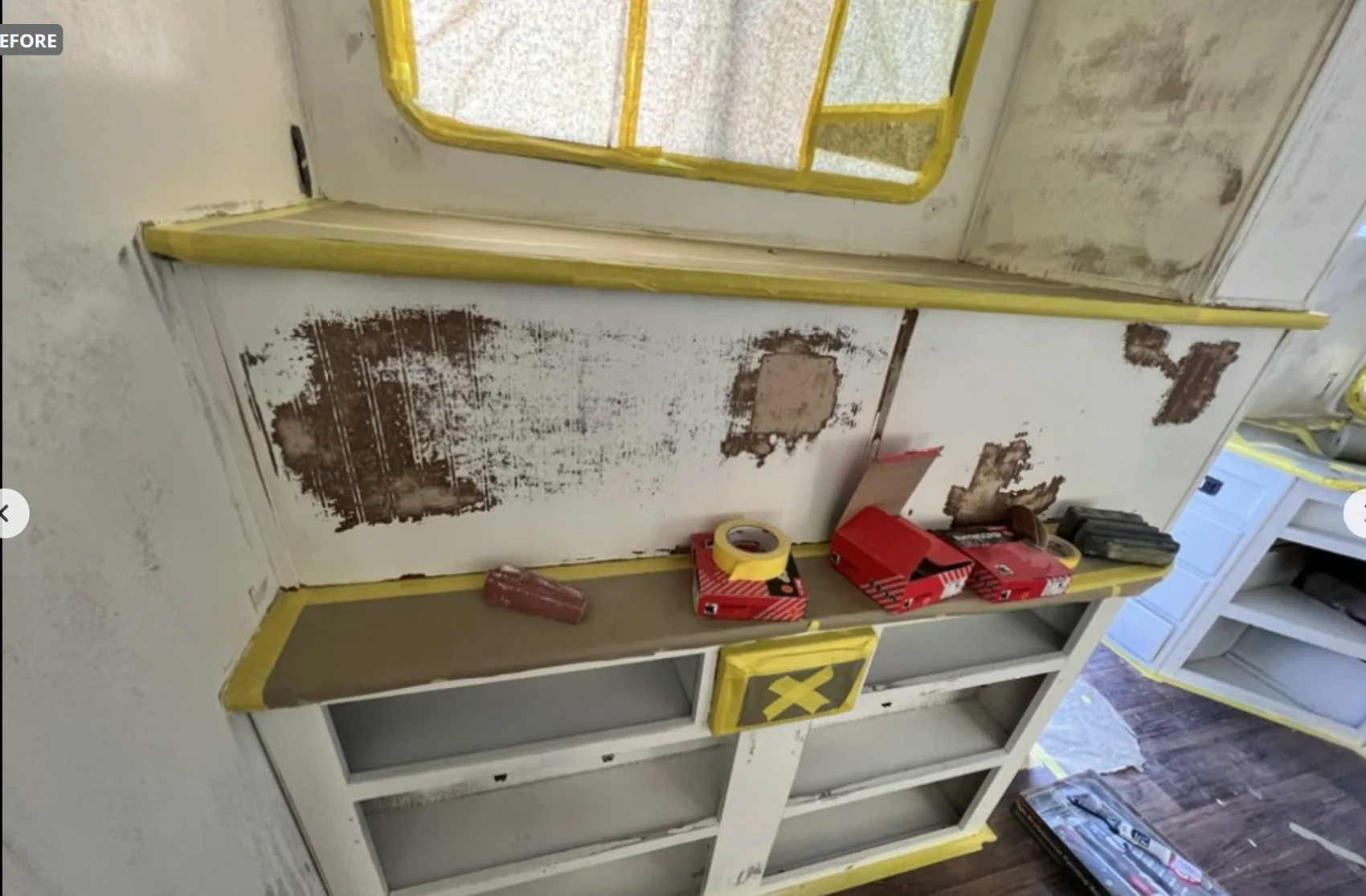 Camper interior during repairs with exposed cabinets and protective tape